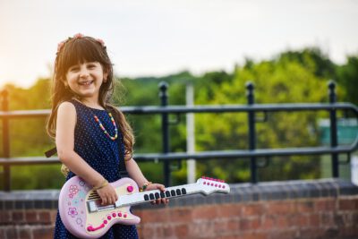 dziewczynka grająca na zabawkowej gitarze