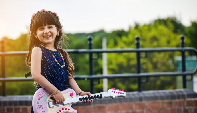 dziewczynka grająca na zabawkowej gitarze