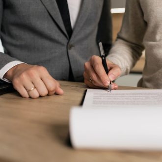 Jeden z dwóch mężczyzn podpisuje dokumenty
