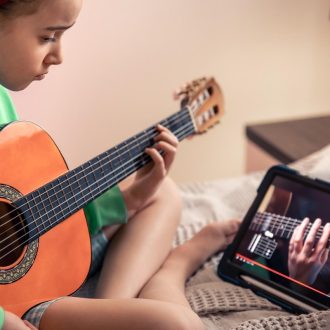 dziewczynka uczy się gry na gitarze online