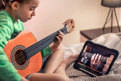 dziewczynka uczy się gry na gitarze online