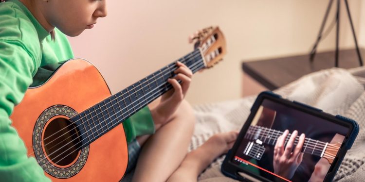 dziewczynka uczy się gry na gitarze online