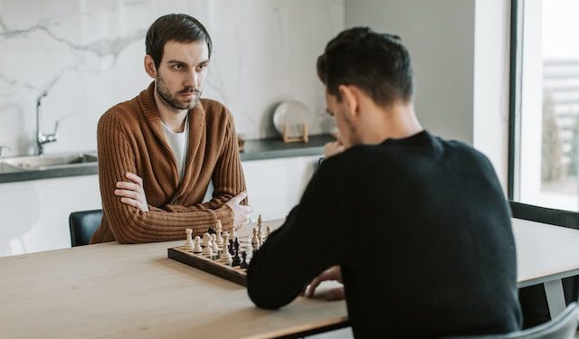 Dwóch mężczyzn grających w szachy przy stole kuchennym
